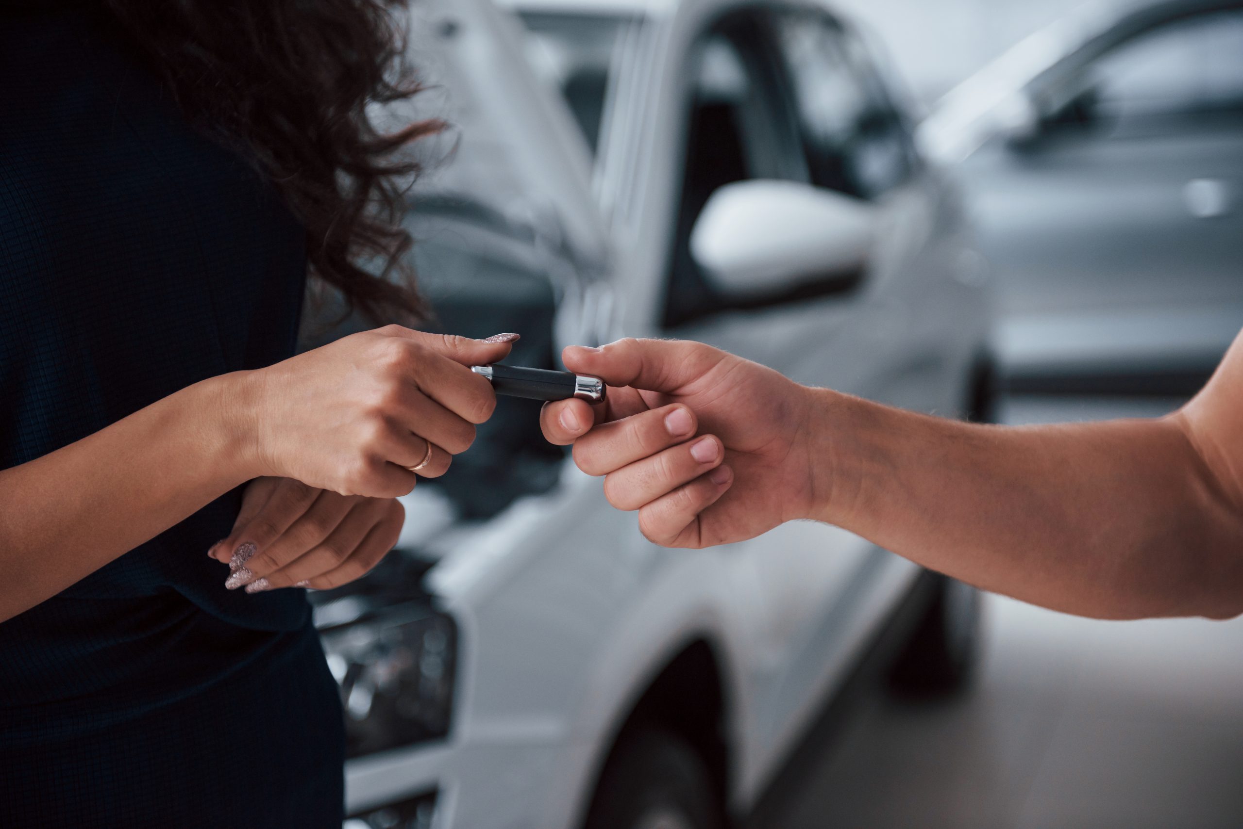 Foco mãos. Homem entregando chave de um carro para uma mulher para ilustrar como saber se o carro é de leilão